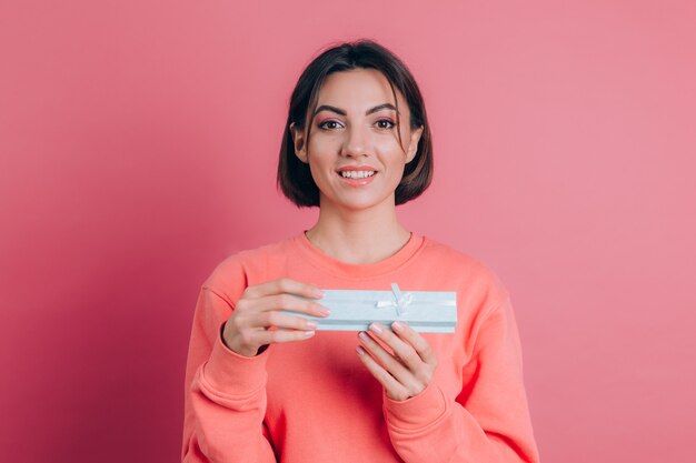 Retrato de niña sonriente feliz abriendo caja de regalo aislado sobre fondo de color rosa