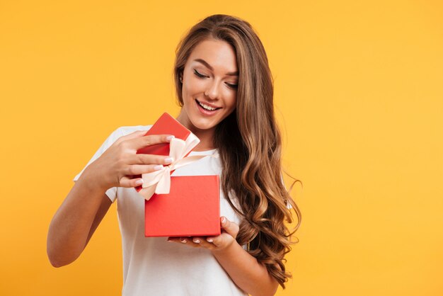 Retrato de una niña sonriente feliz abriendo la caja de regalo