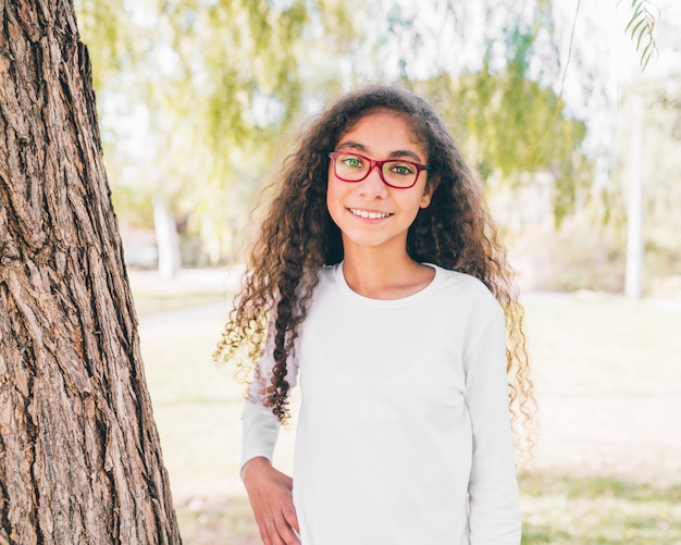 Retrato de una niña sonriente con gafas rojas mirando a cámara