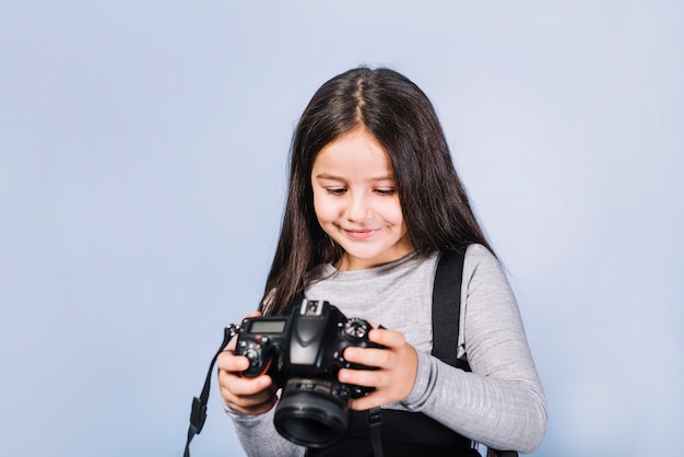 Retrato de una niña sonriente mirando a la cámara contra el telón de fondo azul