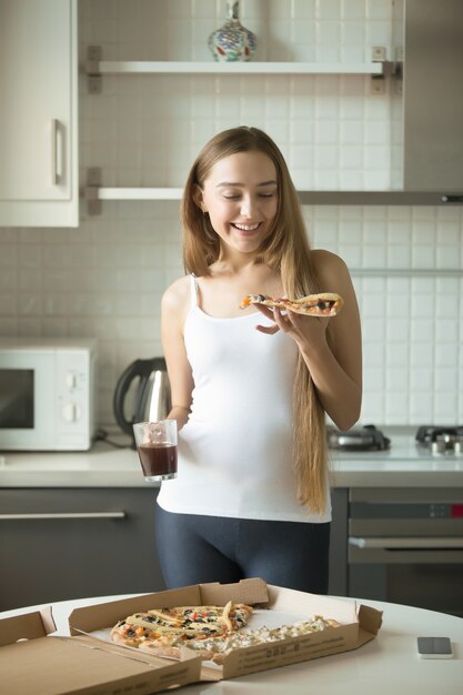 Retrato de niña sonriente de pie, sosteniendo una rebanada de pizza