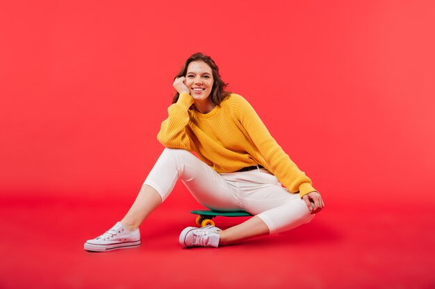 Retrato de una niña sonriente sentada en una patineta