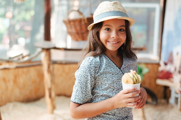 Retrato de una niña sonriente sosteniendo un vaso de rodajas de manzana en el zoológico