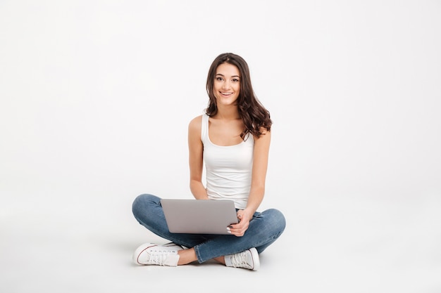 Retrato de una niña sonriente vestida con una camiseta sin mangas con laptop