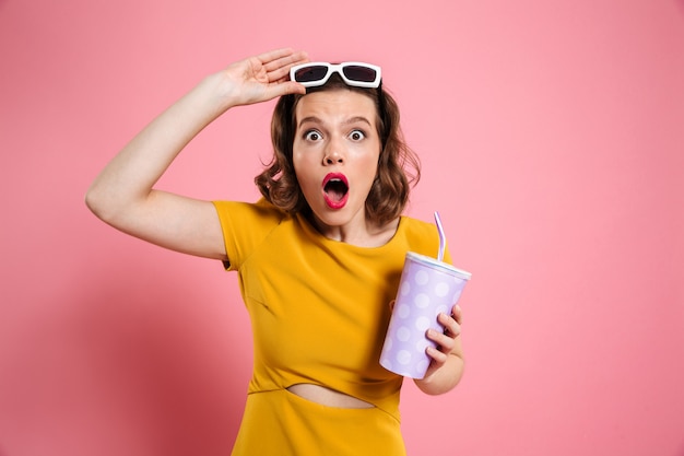 Retrato de una niña sorprendida en gafas de sol con taza