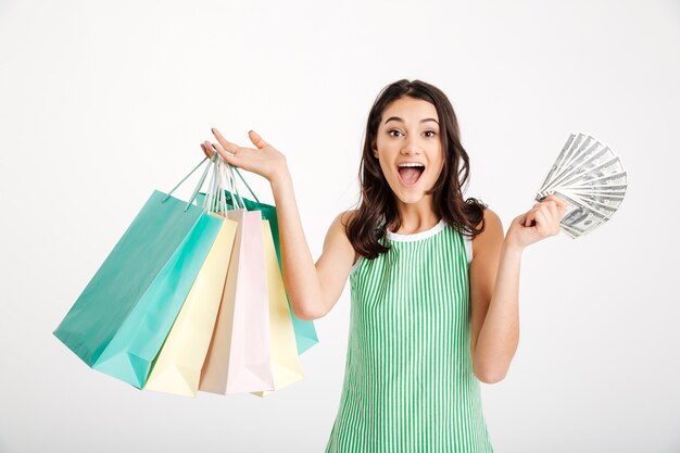 Retrato de una niña sorprendida en vestido sosteniendo bolsas de compras