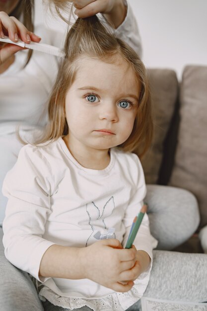 Retrato de una niña con su madre atando su cabello.