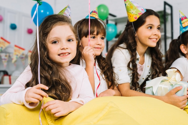 Retrato de una niña con sus amigas disfrutando de la fiesta de cumpleaños.