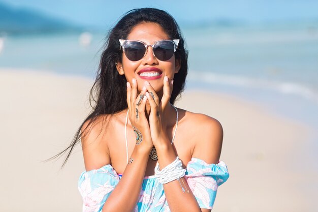 Retrato de niña tailandesa asiática con gafas de sol y vestido de flores divirtiéndose en la playa tropical