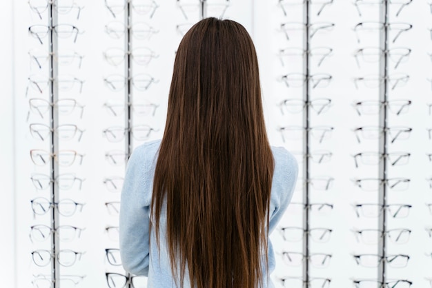 Retrato de niña en la tienda de anteojos eligiendo par