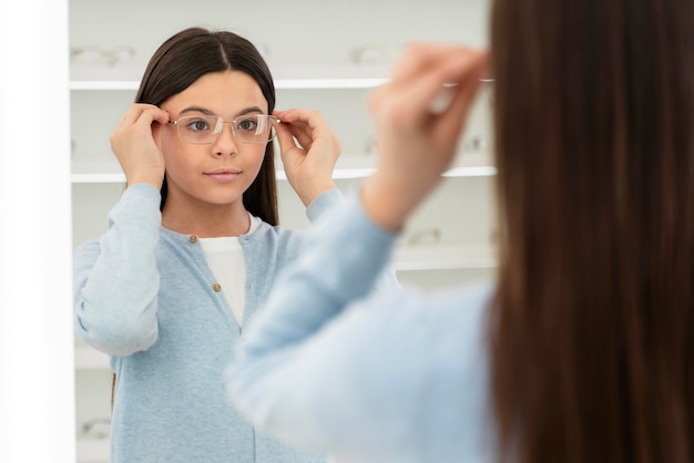 Retrato de niña en la tienda de anteojos probándose gafas