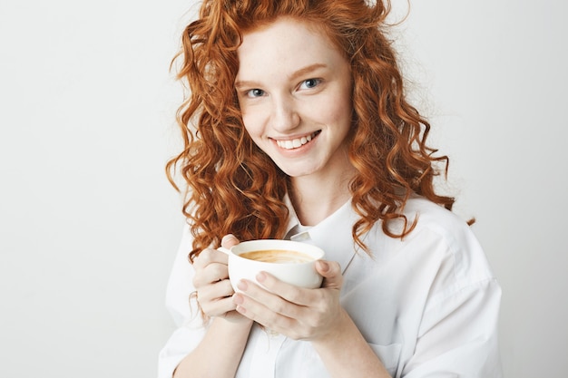 Retrato de niña tierna pelirroja con pecas sonriendo sosteniendo la taza