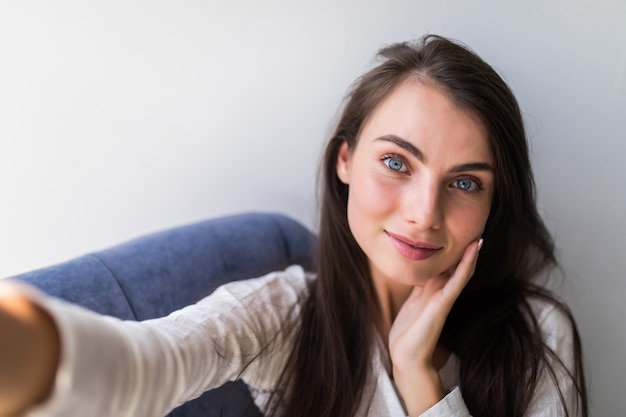 Foto gratuita retrato de niña tomando un autorretrato con su teléfono inteligente en casa.