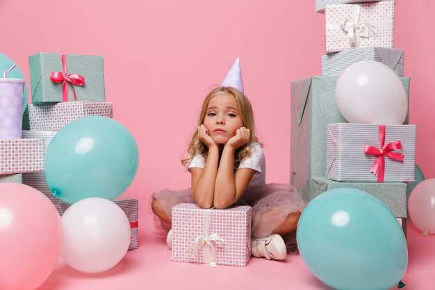 Retrato de una niña triste en un sombrero de cumpleaños