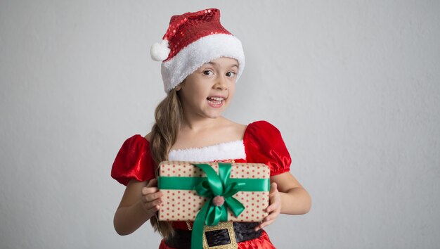 retrato de una niña vestida con un traje de Navidad con un regalo.