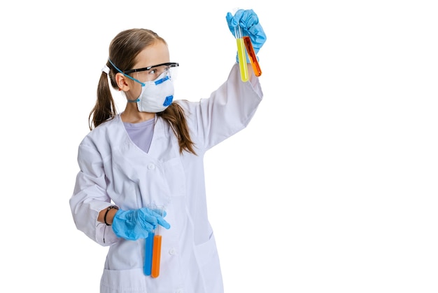 Retrato de niña en vestido blanco como científico químico haciendo experimentos con fluido químico multicolor en laboratorio aislado sobre fondo blanco.