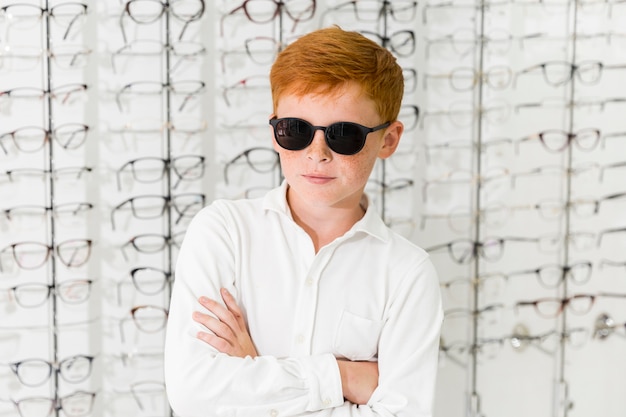 Retrato de niño con anteojos negros de pie contra el fondo de anteojos