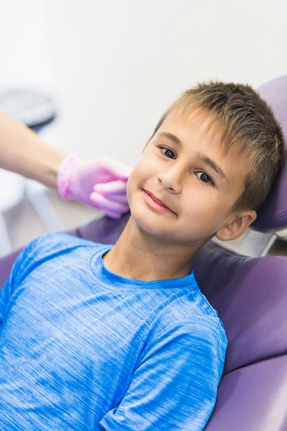 Retrato de un niño apoyado en una silla dental