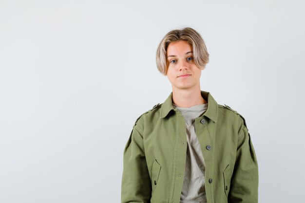 Retrato de niño bonito adolescente mirando a cámara en chaqueta verde y mirando inteligente vista frontal