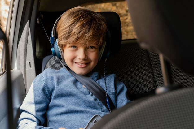 Retrato de niño en coche con auriculares escuchando música