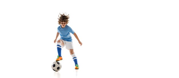 Retrato de niño en edad preescolar, jugador de fútbol en acción, entrenamiento de movimiento aislado en la pared blanca.