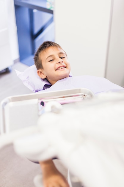 Retrato de un niño feliz acostado en una silla dental