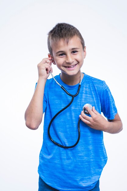 Retrato de un niño feliz escuchando su latido del corazón con un estetoscopio