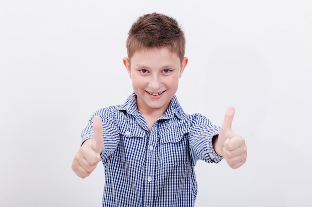 Retrato de niño feliz mostrando los pulgares para arriba gesto