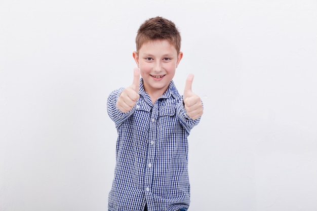 Retrato de niño feliz mostrando los pulgares para arriba gesto