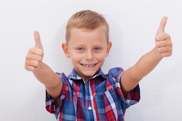 Retrato de niño feliz mostrando pulgares arriba gesto