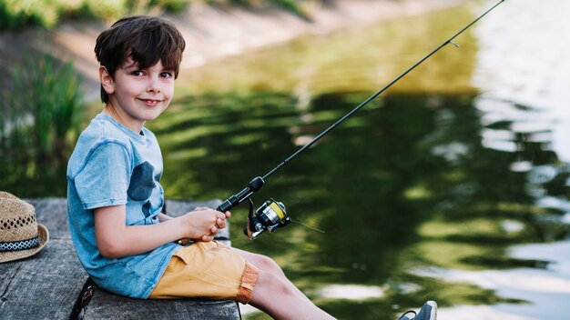 Retrato de un niño feliz pescando en el lago