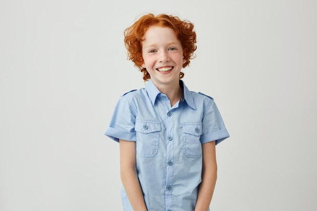 Retrato de niño gracioso con pelo rojo y pecas sonriendo