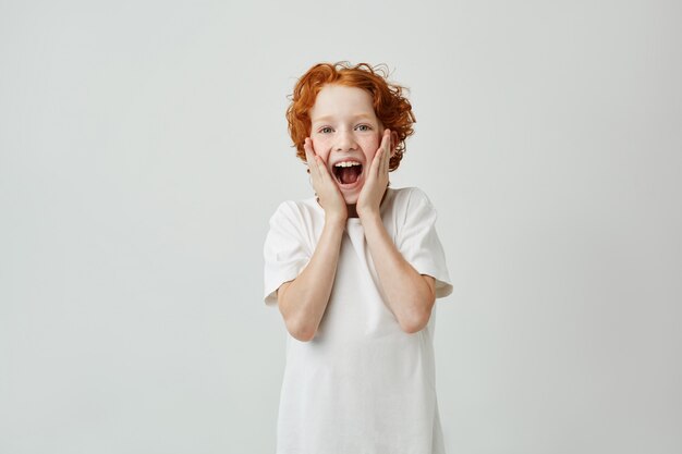 Retrato de niño lindo pelirrojo gritando con expresión feliz