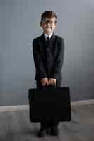 Foto gratuita retrato de niño lindo con traje y maletín