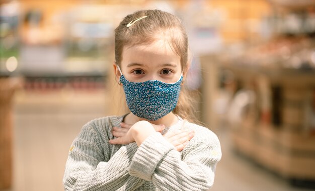 Retrato de un niño con una máscara reutilizable en un supermercado durante la pandemia de covid.