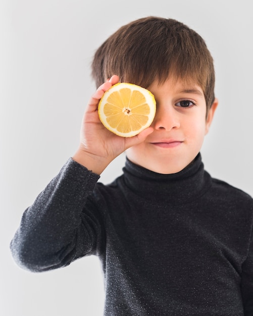 Retrato de niño con media naranja sobre ojo