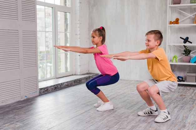 Retrato de un niño y una niña haciendo ejercicio en casa