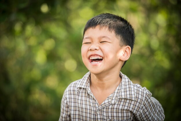 Retrato del niño pequeño feliz que ríe mientras que él juega en el parque.