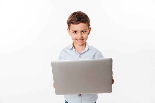 Retrato de un niño pequeño lindo feliz con ordenador portátil