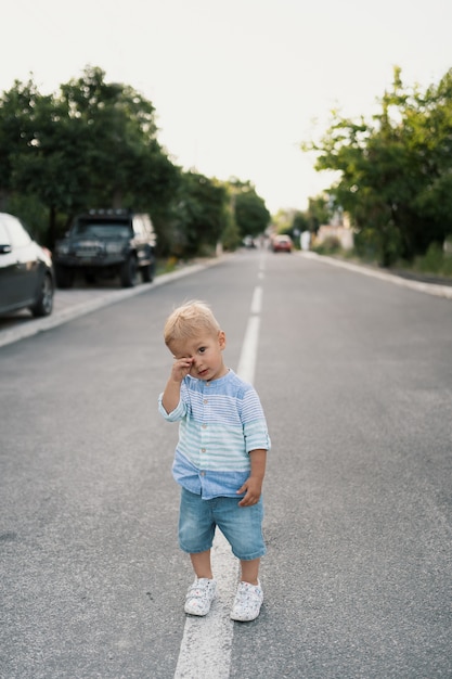 Retrato del niño pequeño lindo que camina en el camino en su vecindario