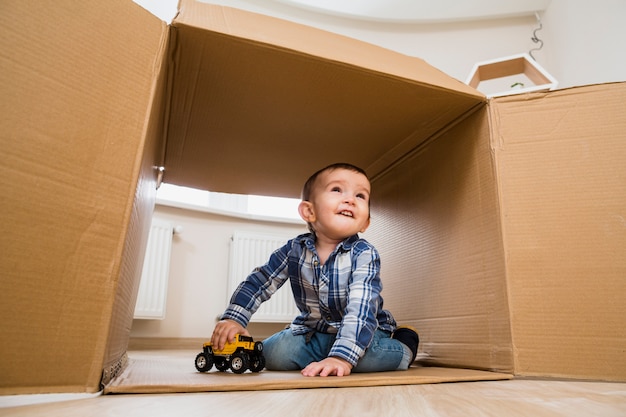 Retrato de un niño pequeño sonriente que juega con los vehículos del juguete