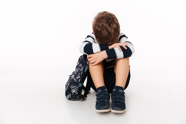 Retrato de un niño pequeño triste molesto con mochila