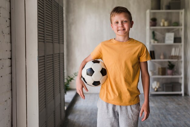 Retrato de un niño sonriente con balón de fútbol