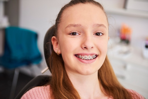 Retrato de niño sonriente con frenillos en el consultorio del dentista