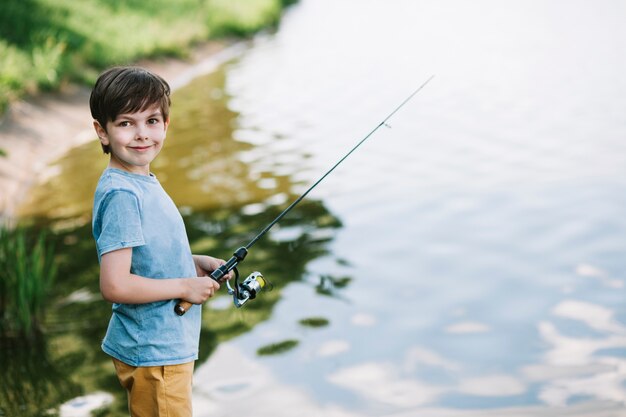 Retrato de un niño sonriente pescando en el lago
