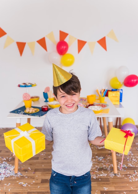 Retrato de un niño sonriente con regalo de cumpleaños en casa