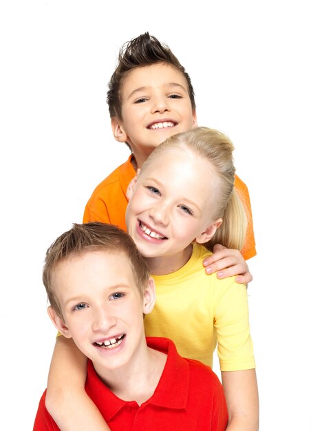 Retrato de los niños felices aislados en blanco. Amigos escolares de pie juntos y mirando a la cámara