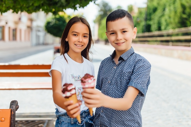 Retrato de niños, hermano y hermana en el banquillo comiendo helado dulce.