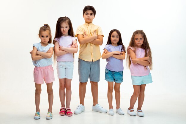 El retrato de niños y niñas lindos felices en ropa casual elegante mirando a la cámara contra la pared blanca