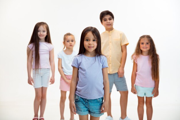 El retrato de niños y niñas lindos felices en ropa casual elegante mirando a la cámara contra la pared blanca